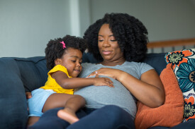 African,American,Llittle,Girl,Holding,Her,Mother's,Stomach.